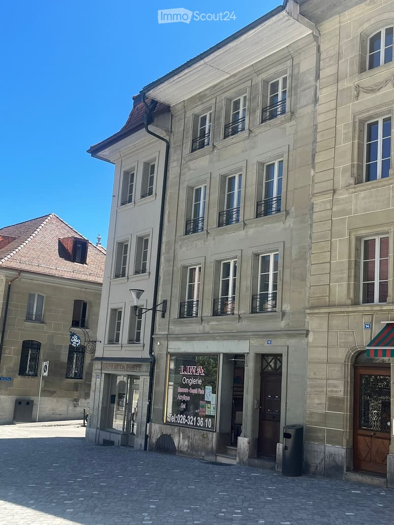 A multi-story building with classic European architecture, featuring large windows, balconies, and a storefront with signage for "LINA Onglerie" on the ground floor.