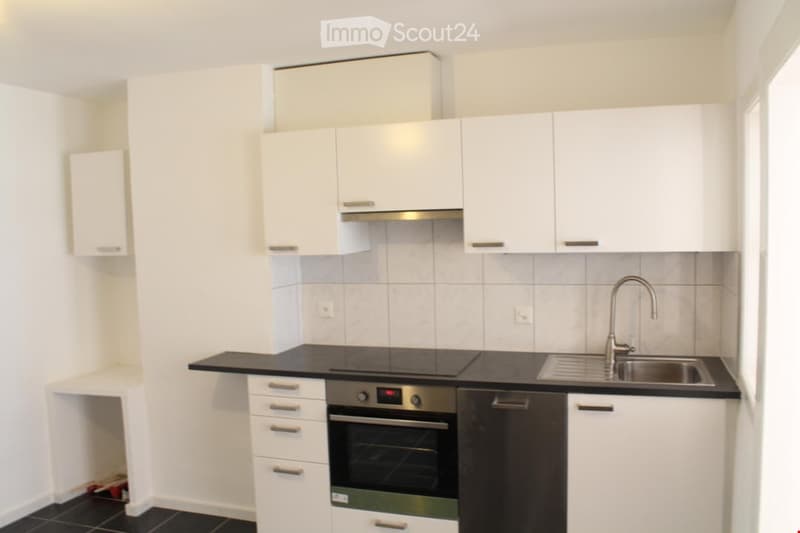Modern kitchen with white cabinets, black countertops, stainless steel sink, and built-in oven.