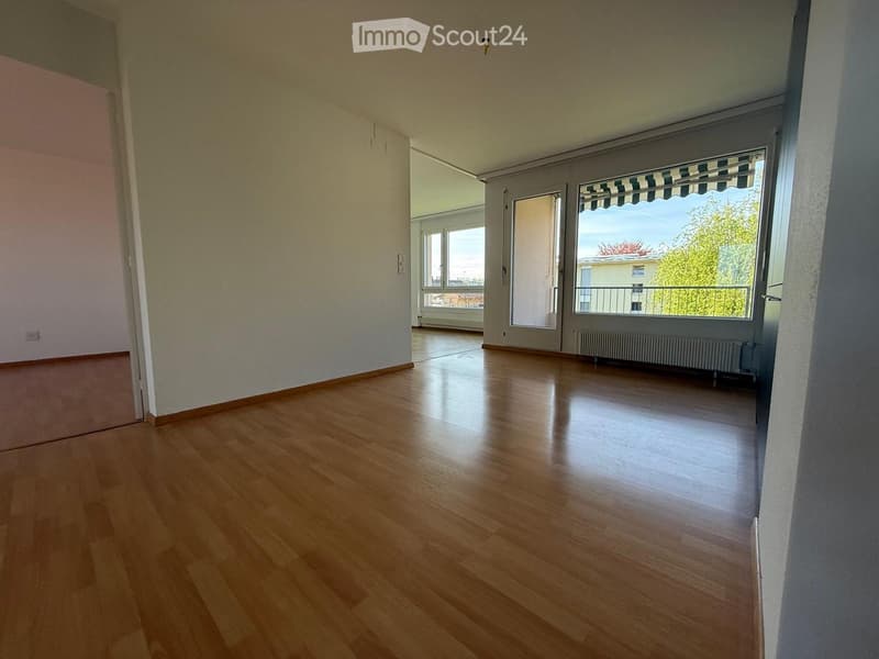 Empty room with wooden flooring, large windows, and a radiator. No furniture or equipment present.