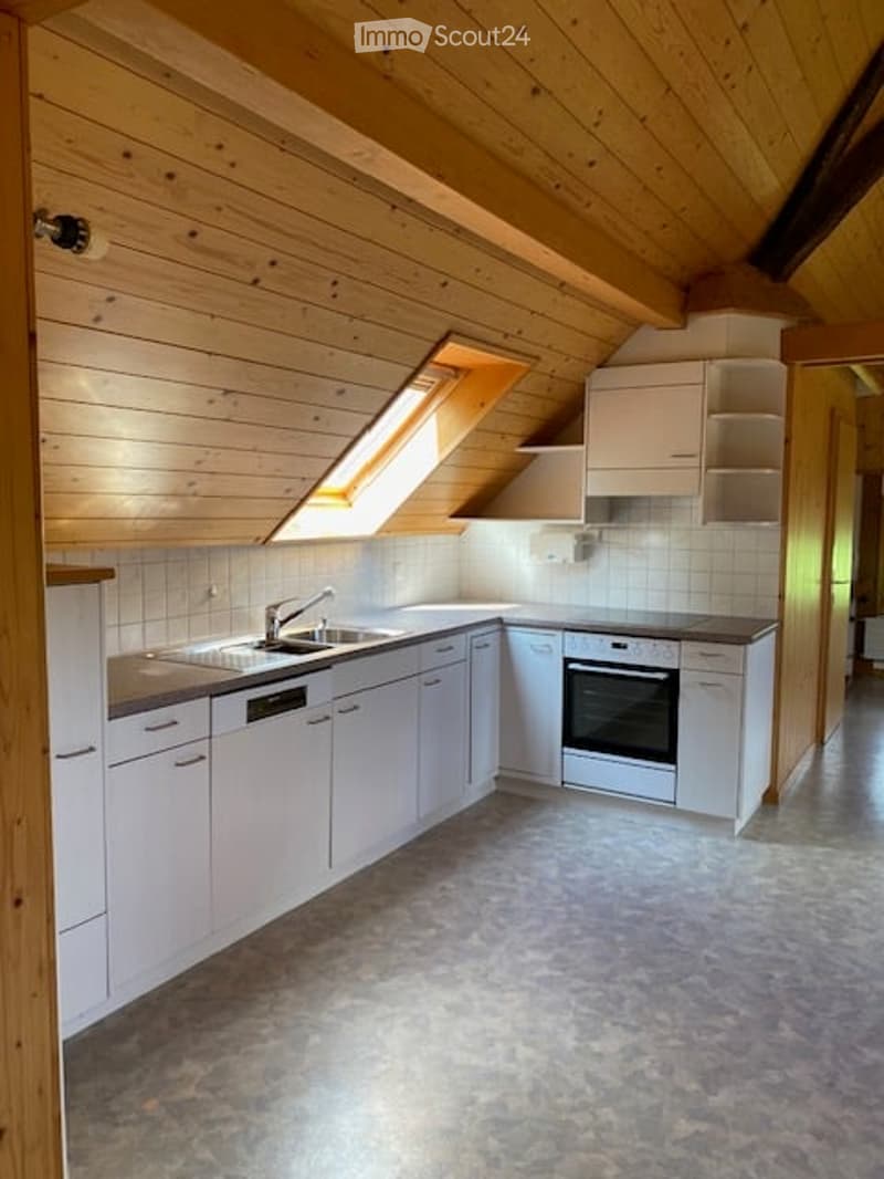 Bright kitchen with wooden ceiling beams, white cabinets, and a built-in oven. Features a sink with a modern faucet and ample counter space.