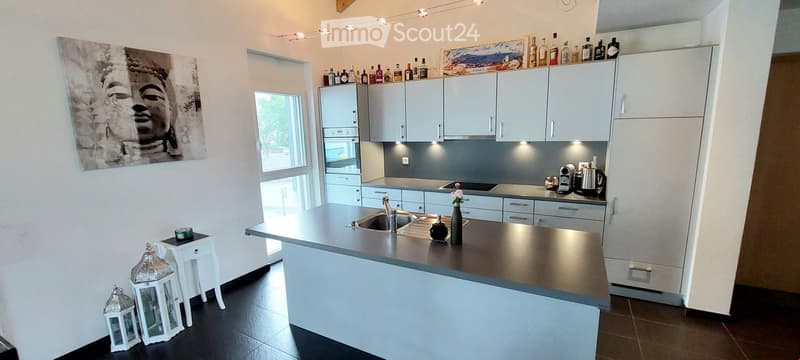 Kitchen. Modern kitchen with white cabinets, stainless steel appliances, and a central island. Features include a sink, coffee maker, and decorative lanterns on the floor.