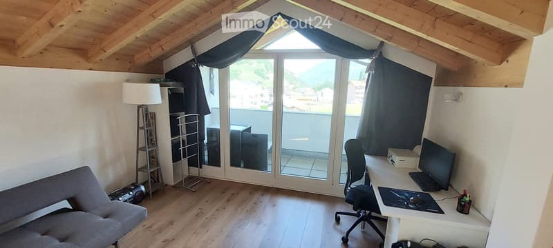 Furnished Room. Bright attic room with wooden ceiling, large window offering a scenic view, sofa, desk with laptop, chair, and lamp.