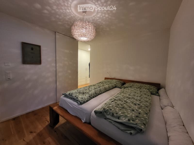 two beds, green sheets, wooden bed, white walls, wooden floor, decorative lamp