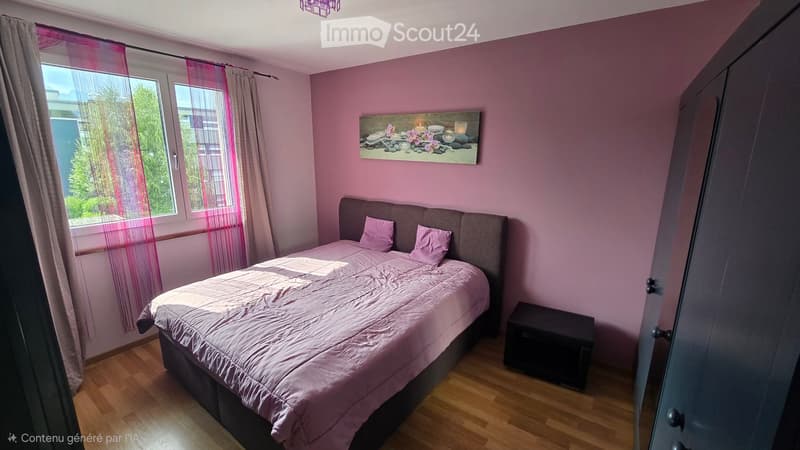 Cozy bedroom with pink walls, wooden floor, large window with sheer curtains, bed with pink bedding, nightstand, and decorative picture frame on wall.