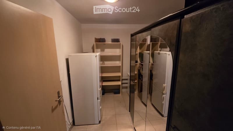 A small hallway with a refrigerator on the left and a shelf with items on the right. The floor is tiled, and the walls are painted in a light color.