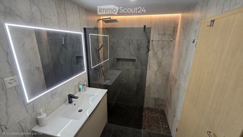Modern bathroom with marble walls, a white sink with a black faucet, a large illuminated mirror, a glass-enclosed shower, and a wooden cabinet.