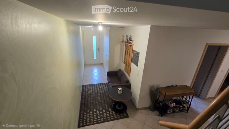 A small, well-lit hallway with a sofa, a round table, a rug, a shoe rack, and a small shelf with decorative items.