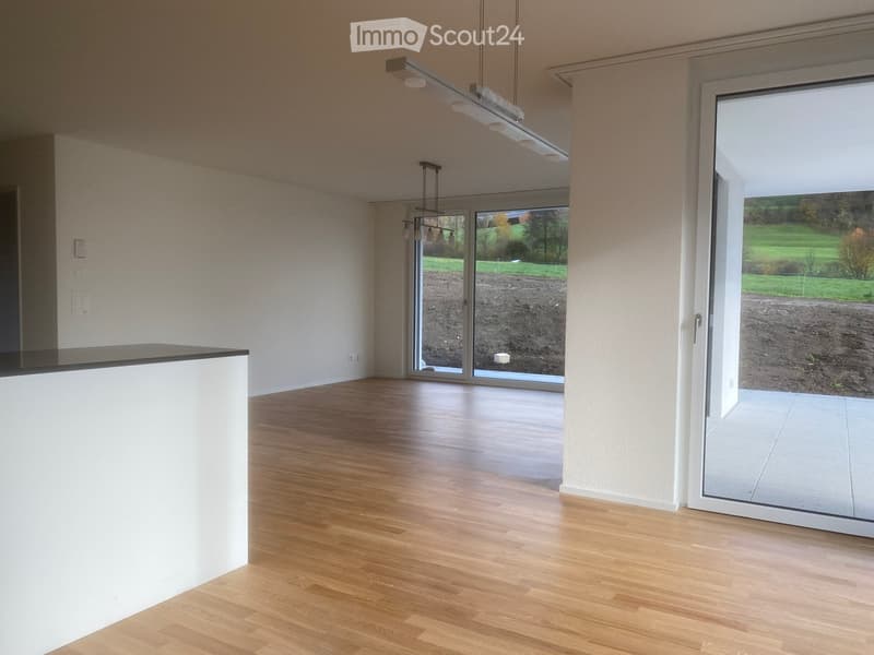Empty room with wooden flooring, white walls, and large glass doors leading to an outdoor area.