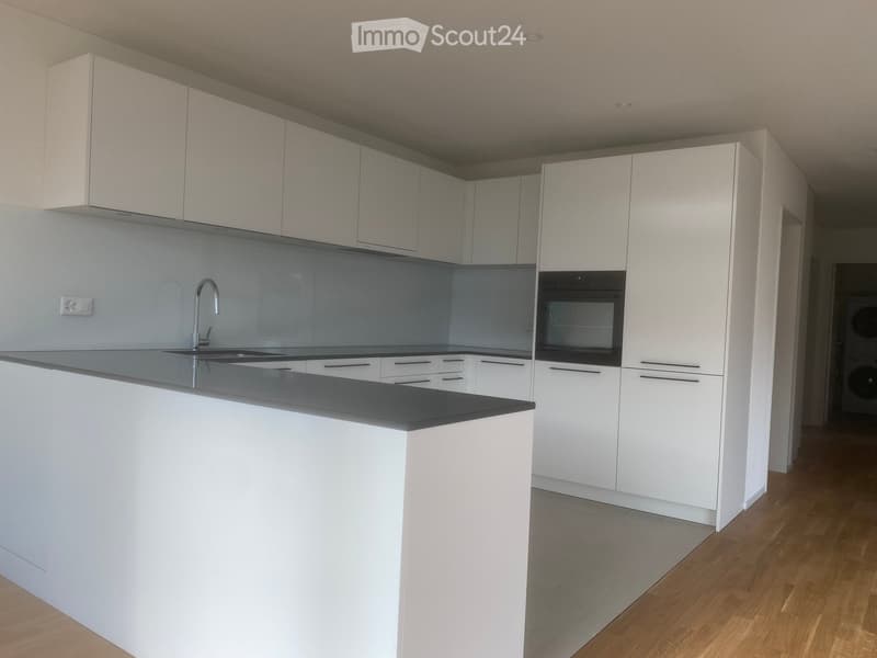 Modern kitchen with white cabinets, a central island, and a stainless steel sink and faucet.