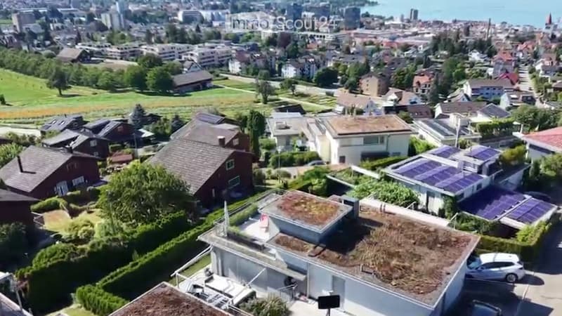 Aerial view of a suburban neighborhood with multiple houses, green lawns, and solar panels on some roofs.
