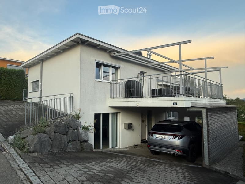 Two-story modern house with white exterior, large windows, balcony, garage, and a parked car.