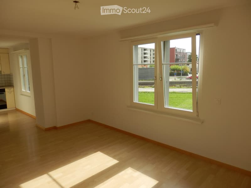 Empty room with wooden flooring, large windows, and white walls. No furniture or equipment visible.