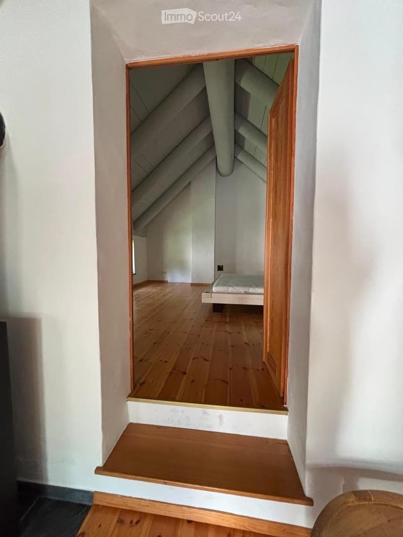 A narrow, wooden staircase leads up to an attic space with exposed wooden beams and a slanted ceiling.