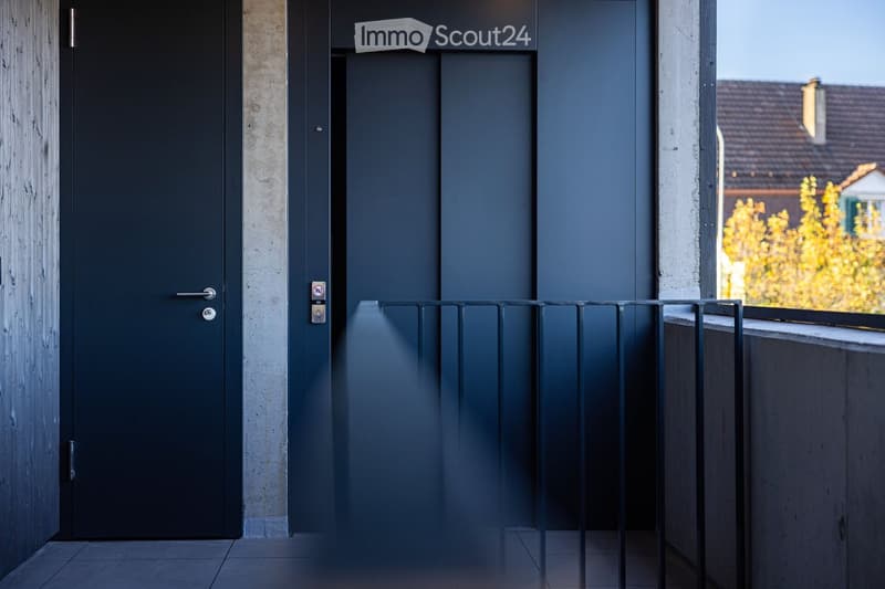 A corridor with a closed door, an elevator door, and a railing.