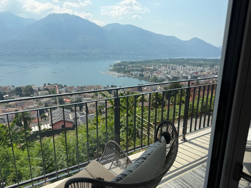 Balcony with a scenic view of a lake and mountains, featuring a single chair.