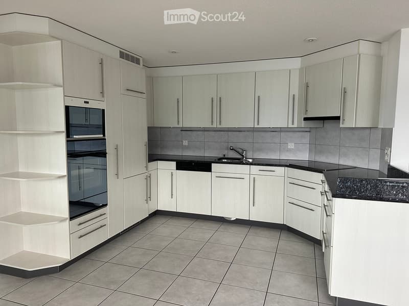 Modern kitchen with white cabinets, granite countertops, tiled floor, and built-in oven.