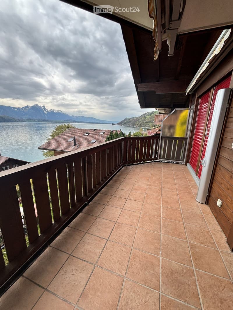 Balcony with tiled floor, wooden railing, and scenic mountain and lake view.
