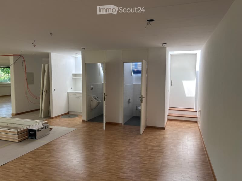 Empty hallway with wooden flooring, open doors leading to bathrooms, and exposed construction materials and boxes.