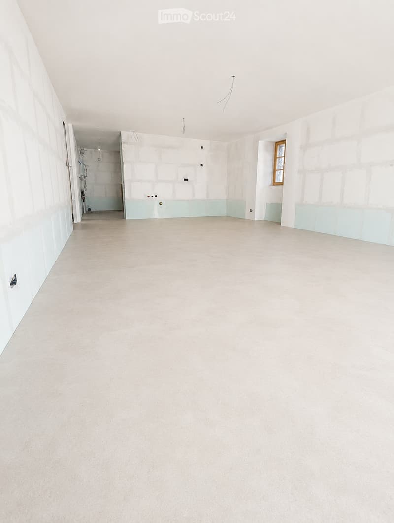 Empty room with light-colored tiled floor and white walls, featuring a small window and an open doorway leading to another area.