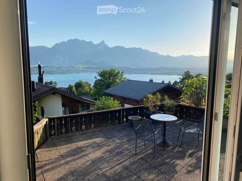 Balcony with a scenic mountain and lake view, featuring a small round table and two chairs.