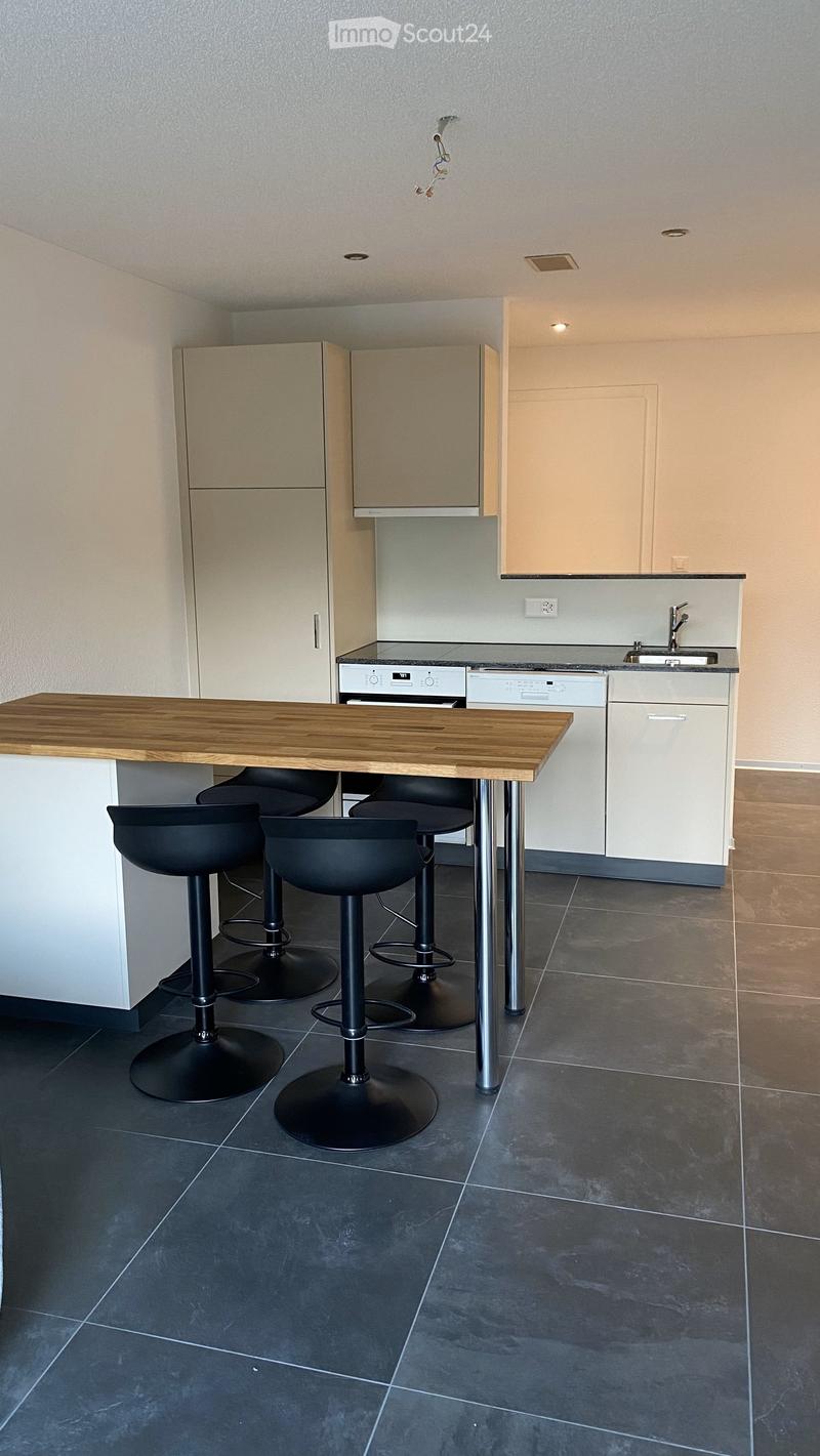 modern kitchen with island, white cabinets, black stools, dishwasher, washing machine, granite countertop, stainless steel appliances