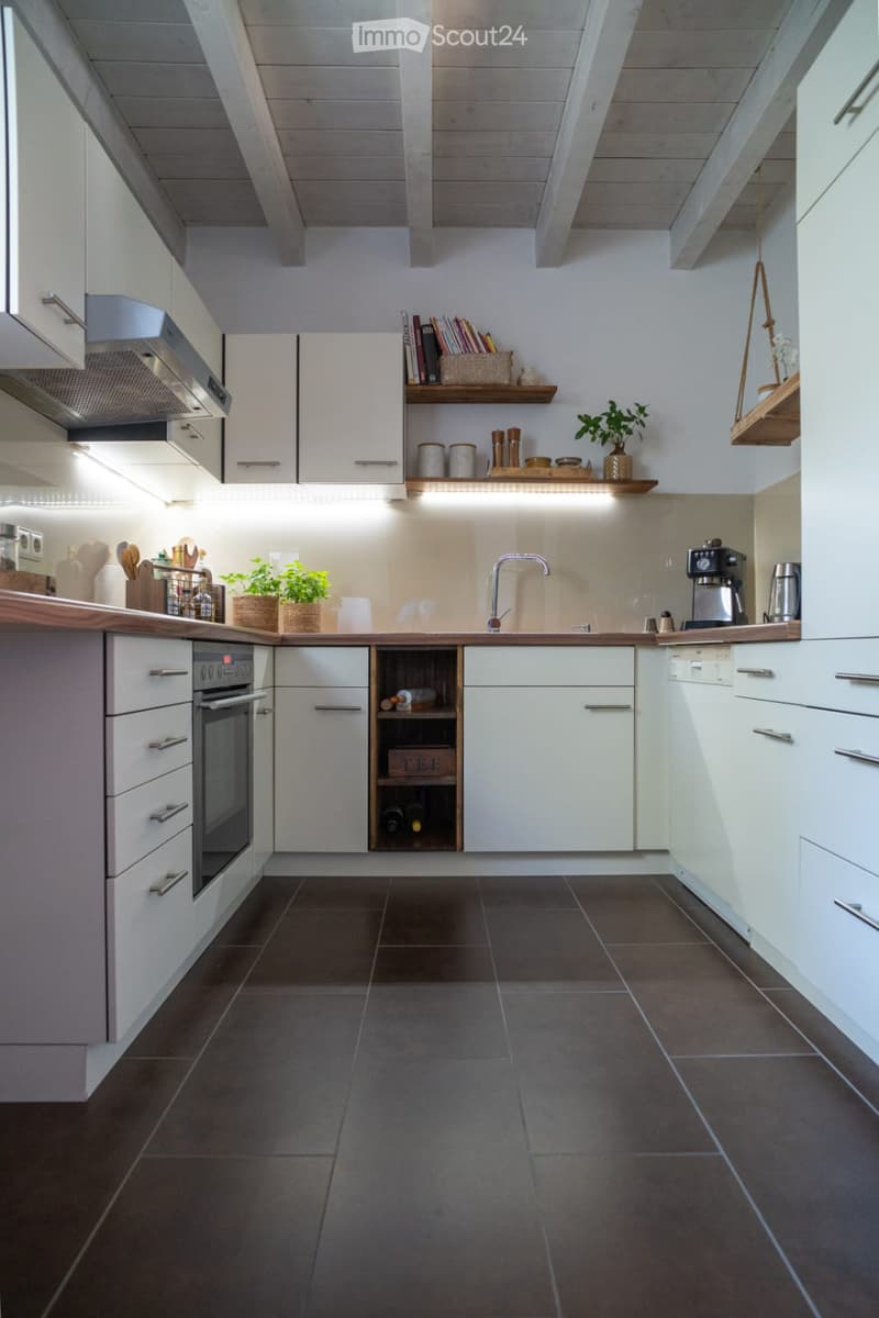 Modern kitchen with white cabinets, dark tiled floor, stainless steel appliances, wooden countertop, and built-in wine rack.