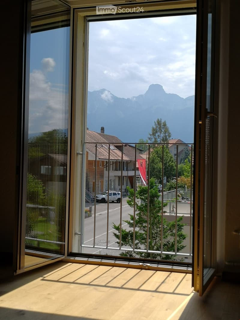 Balcony with wooden floor, metal railing, and scenic mountain view.