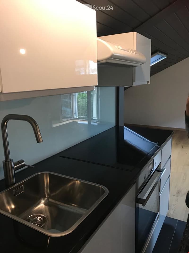 Modern kitchen with stainless steel sink, faucet, black countertops, white cabinets, and built-in oven.
