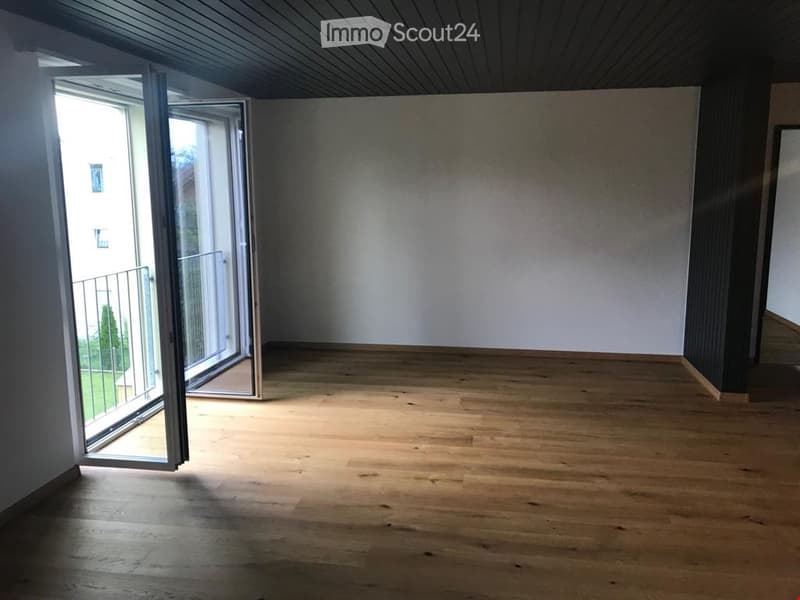 Empty room with wooden flooring, white walls, and large sliding glass doors leading to a balcony.