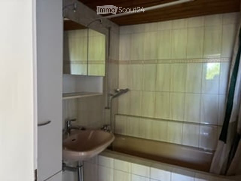 Bathroom with white tiled walls, a pink sink, a mirror, a bathtub, and a shower curtain.
