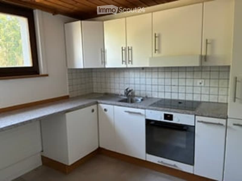 Bright kitchen with white cabinets, tiled backsplash, and stainless steel appliances.