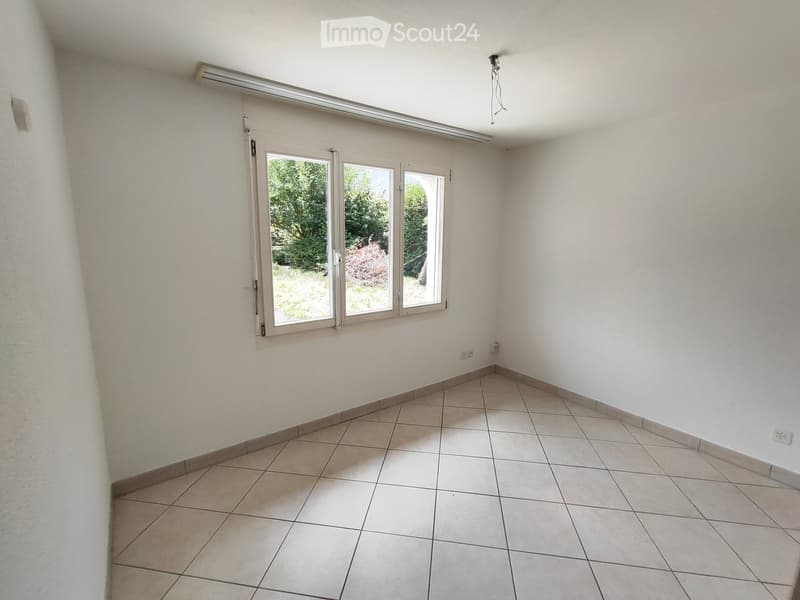 Empty room with tiled floor and white walls, featuring large windows with blinds and visible electrical outlets.