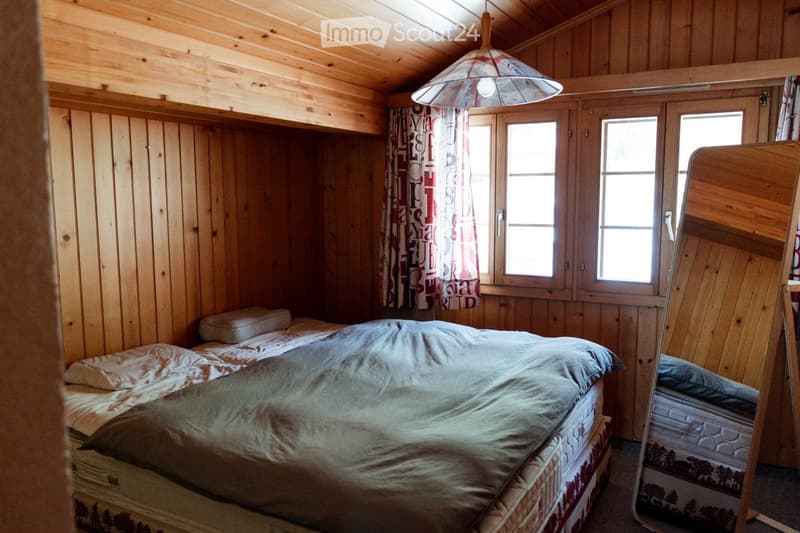 Cozy wooden bedroom with two single beds, a mirror, and curtains on the windows.