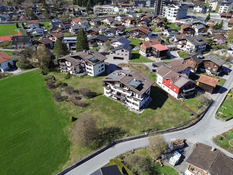 Aerial view of a residential area with multiple houses, green spaces, and roads.