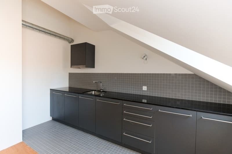 Modern kitchen with dark grey cabinets, black countertop, and stainless steel sink.