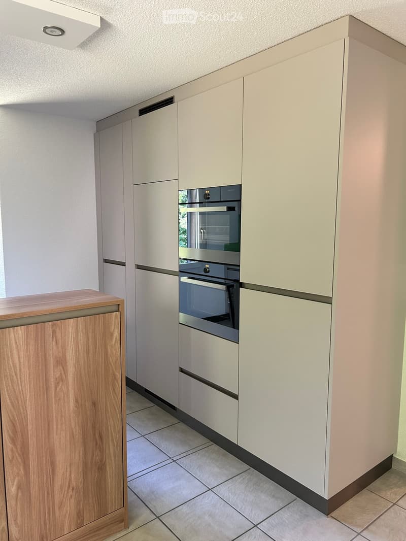 Modern kitchen with light-colored cabinets, a built-in oven, and a wooden countertop.