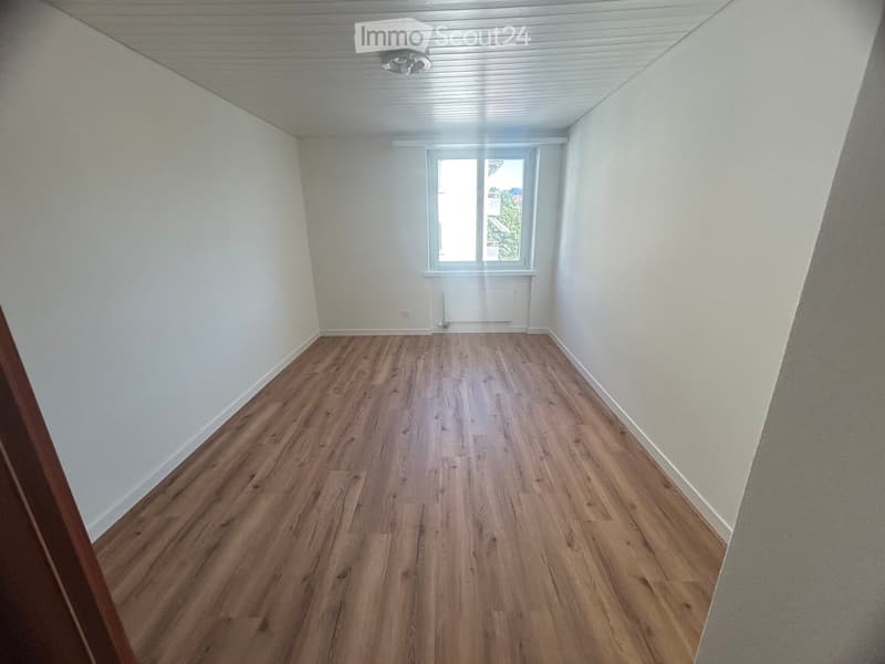 Empty room with wooden flooring, white walls, and a window letting in natural light. No furniture or equipment is present.
