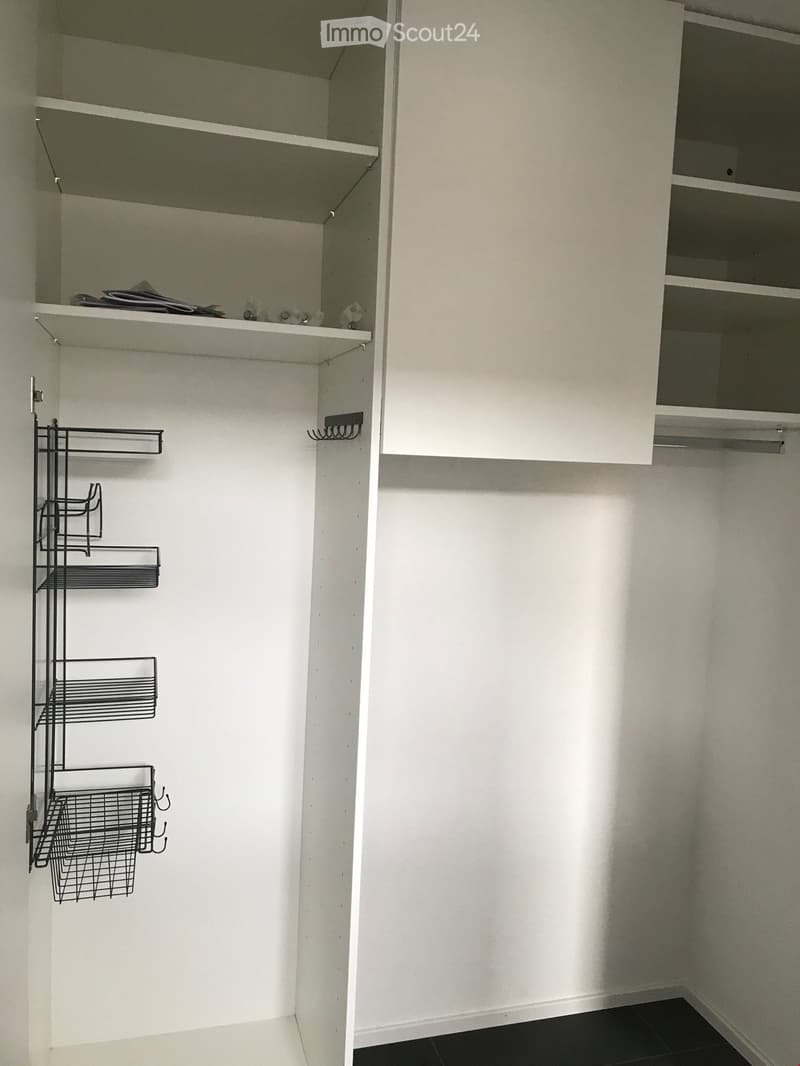 White wardrobe, shelves, hanging rod, metal rack, open door, white walls, black floor