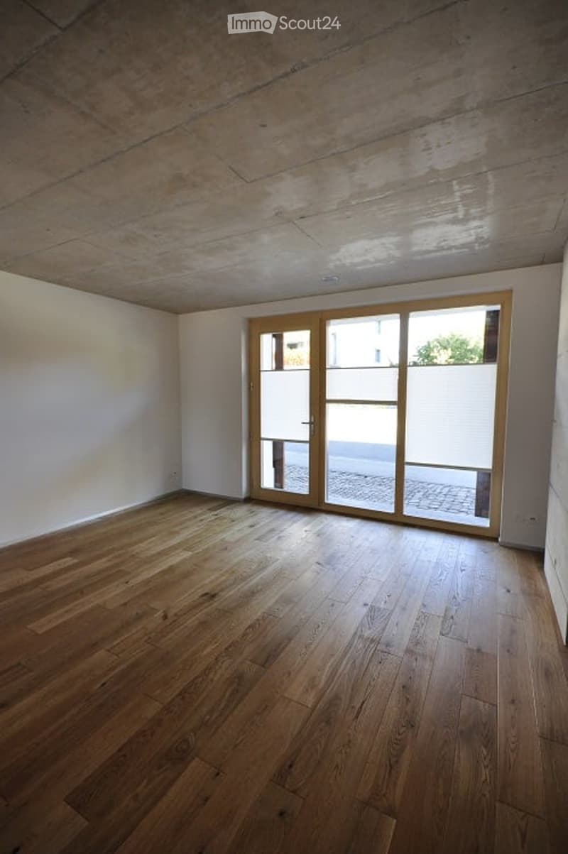Empty room with wooden flooring and large glass sliding doors leading to an outdoor area.