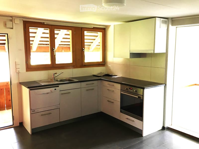 modern kitchen with white cabinets, black countertops, stainless steel sink, dishwasher, oven, and windows