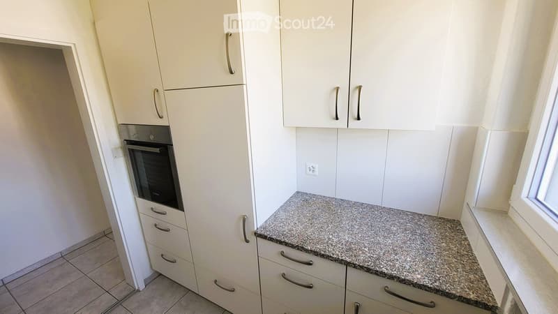 Modern kitchen with white cabinets, granite countertop, and built-in oven.