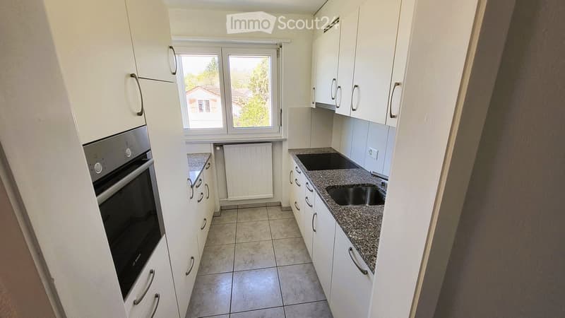 Modern kitchen with white cabinets, granite countertop, stainless steel oven, and double sink.