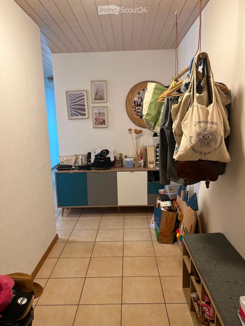 Hallway with tiled floor, coat rack, storage cabinet, and various personal items including bags and shoes.