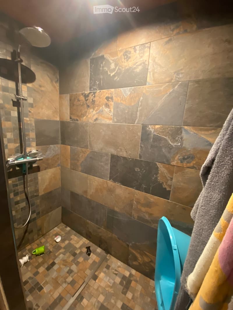 Shower area with marble tiles, a showerhead, and a towel hanging on the side.