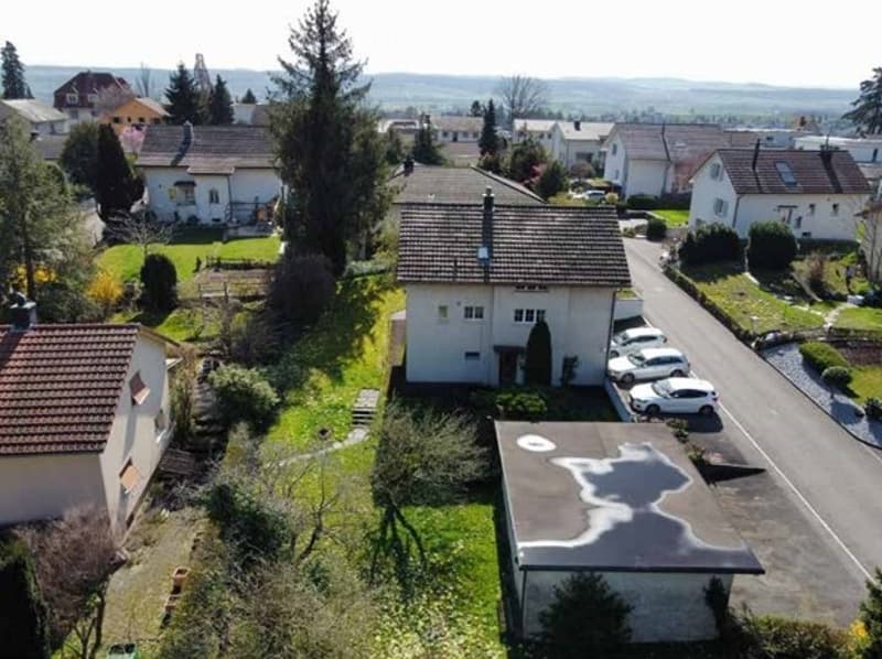 House in a row of houses, brown roof, car parked in front, garden, multiple other houses