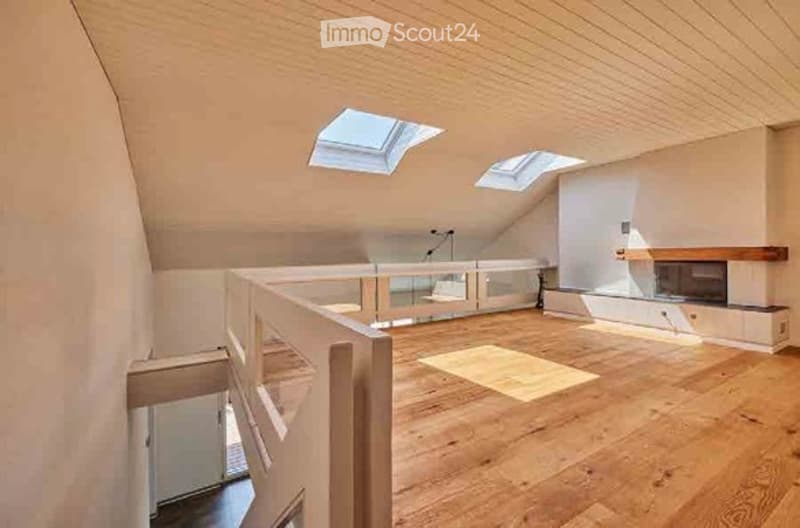 Bright, open attic space with wooden flooring, skylights, and a fireplace. No furniture present.