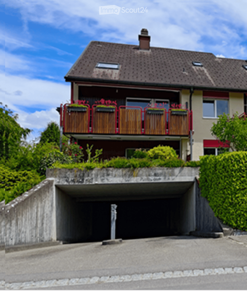 Two-story house with a garage, balcony, and garden area.