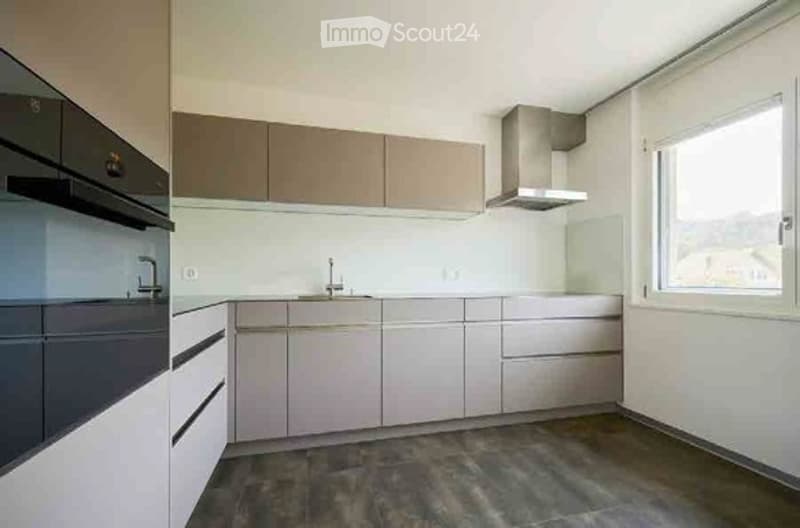 Modern kitchen with light-colored cabinets, stainless steel appliances, and a large window providing natural light.