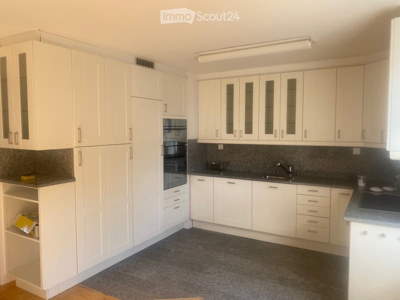 Modern kitchen with white cabinets, dark countertops, and built-in appliances including an oven and sink.