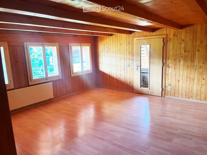 Empty room with wooden walls, wooden floor, and large windows. No furniture or equipment present.